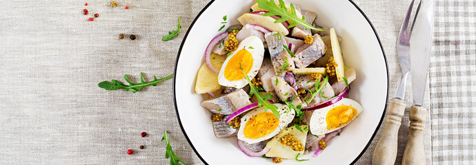 Traditional  salad of salted herring fillet, fresh apples,  red onion  and eggs. Kosher food. Scandinavian cuisine. Top view. Flat lay. Banner.