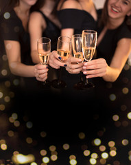 Cheers! Group of people cheering with champagne flutes with holiday lights on background with copy space.