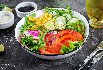 Vegan buddha bowl. Bowl with fresh raw vegetables - cucumber, tomato, watermelon radish, lettuce, arugula and corn. Fresh salad. Vegetarian food.