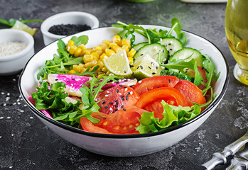 Vegan buddha bowl. Bowl with fresh raw vegetables - cucumber, tomato, watermelon radish, lettuce, arugula and corn. Fresh salad. Vegetarian food.