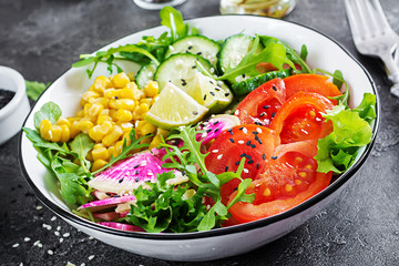 Vegan buddha bowl. Bowl with fresh raw vegetables - cucumber, tomato, watermelon radish, lettuce, arugula and corn. Fresh salad. Vegetarian food.