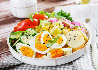 Fresh salad. Vegetarian buddha bowl. Bowl with boiled potato, cucumber, tomato, watermelon radish, lettuce, arugula, corn and boiled egg.  Healthy food.