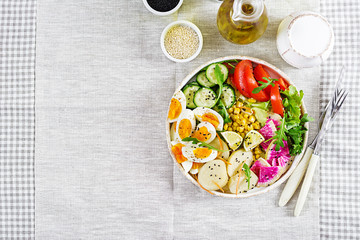 Fresh salad. Vegetarian buddha bowl. Bowl with boiled potato, cucumber, tomato, watermelon radish, lettuce, arugula, corn and boiled egg.  Healthy food. Top view. Flat lay