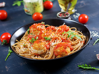 Italian pasta. Spaghetti with meatballs and parmesan cheese in black plate on dark rustic wood background.  Dinner. Slow food concept