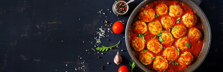 Chicken meatballs with tomato sauce in a pan. Dinner. Top view. Banner.  Dark background. - obrazy, fototapety, plakaty
