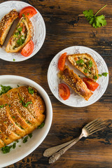 Meatloaf in dough, meat pie. White baking dish and plates on wooden rustic table, top view