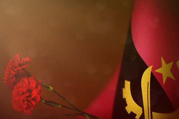 Angola flag for honour of veterans or memorial day with two red carnation flowers. Glory to Angola...