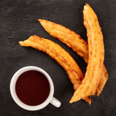 Traditional Spanish porras with hot chocolate, a typical Madrid Sunday breakfast, shot from the top on a black background with copy space