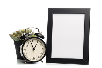 black photo frame and clock isolated on white background, succulent behind.