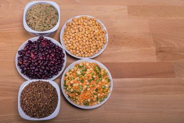 The concept of natural healthy food. Grains of various beans in ceramic cups on wooden background