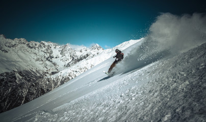Snowboardzista jadący szybko w głębokim puchu i wzbijający firanę śniegu