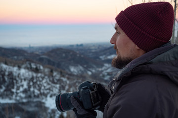The guy with the camera, early in the morning in the winter in the mountains, looking out for the plot