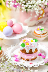 Traditional Easter cake with white icing decorated sugar flowers and colorful eggs.
