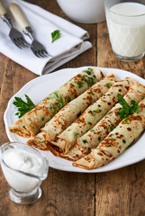 Russian pancakes with fresh green onions and parsley on a plate
