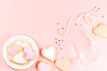 Happy Valentine's day greeting card with heart cookies, wine glasses and wine on pastel pink background.