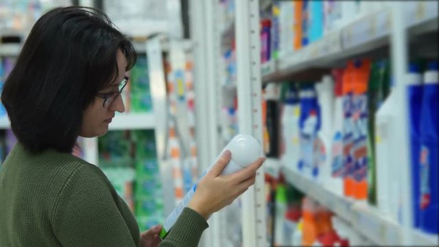Woman buying air freshener and spray detergent in the department of home care products in the hypermarket