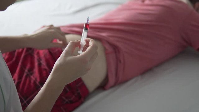 A nurse makes an injection with medicine in the ass of a sick man. Treatment at home. She inserts a shot and injects the vaccine intramuscularly.