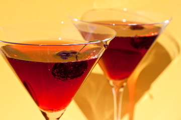 Red cocktail with cherry on yellow  background