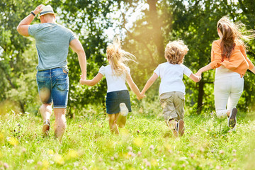 Fototapeta premium Aktive Familie und Kinder laufen über Wiese