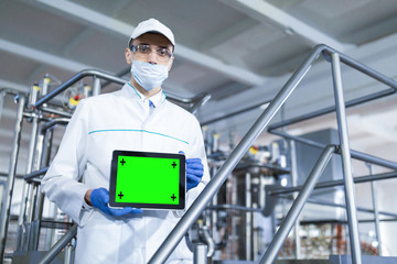 man in a white robe and a mask with a tablet in his hands is at the factory