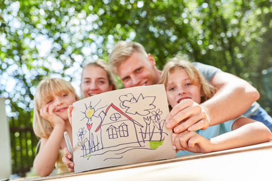 Familie zeigt bunte Zeichnung mit Eigenheim