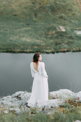 Fototapeta na wymiar Boudoir morning bride in nature in a white dress. Wedding series on cliffs and river bends.