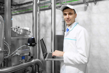 Technologist with a laptop in his hands at the dairy plant