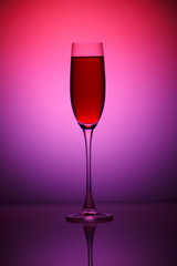 Red wine in а glass on pink  background.