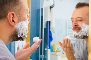 Guy shaving his beard in bathroom