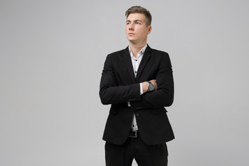 Portrait of young man in black suit with arms crossed isolated on white background