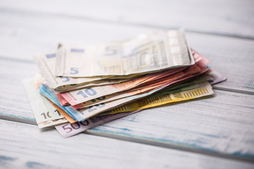 Close-up a pile of banknotes lying on a wooden table.