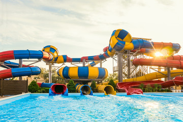 Long spiral water slides in the outdoors seasonal water park at evening sun