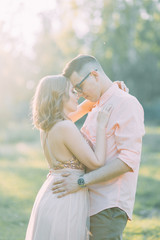 Beautiful couple in the forest at sunset in the style of fine art. Photo shoot in nature with the sun.