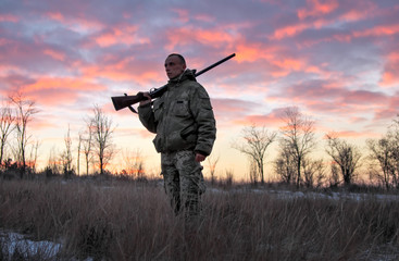 Winter hunting at sunrise. Hunter moving With Shotgun and Looking For Prey.