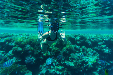 Young beauty woman showing okay sign at snorkeling at reef in the tropical water