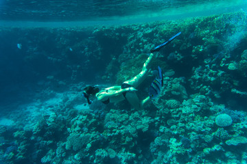 Young woman snorkeling over coral reefs in a tropical sea