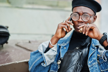 African american man in jeans jacket, beret and eyeglasses, with cigar posed against btr military...