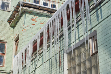 Fototapeta na wymiar Large, dangerous icicles hang on the building.