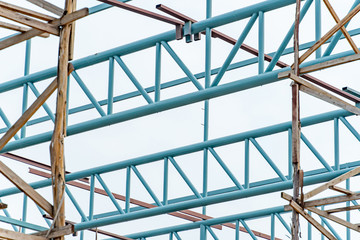 Steel truss structure with wooden scaffolding at construction site. Structural engineering concept