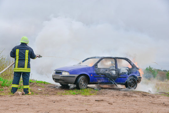 Fire fighter prepare to attack a propane fire. Burning and crashed car after explosion. Accident on street at countryside. No one was injured. Artificially created set for film making
