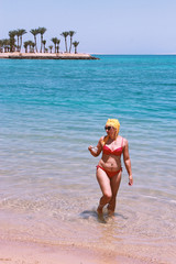 Girl enjoying rest drinking coffee on beach. Woman relaxing standing in sea
