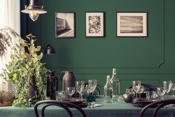 Black and green design of elegant dining table in fashionable interior with gallery of posters on the wall