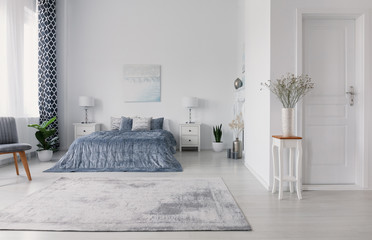 New york style bedroom design with double bed, white bedside tables with lamps, plush carpet and...