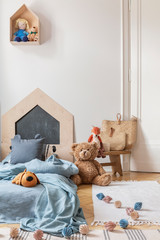 Real photo of a cozy child bedroom interior with a bed, toys and lamps chain on a floor