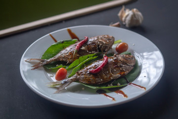 smoked, fried fish on a white plate with spices