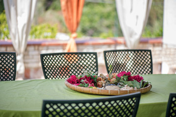 Garden terrace table set up for a lovely brunch on the weekend. Flower petals put in a woven basket to create a Sicillian atmosphere. 