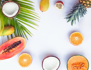 Creative frame with tropic fruits and palm leaf on the white background,