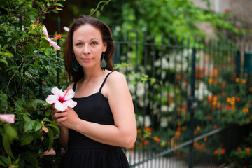 Young attractive woman in black dress posing with pink flowers