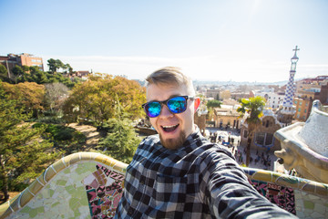 Travel and holidays concept - Happy guy making selfie portrait with smartphone in Park Guell,...