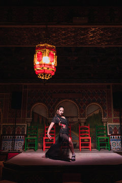 Woman in dress dancing flamenco on scene